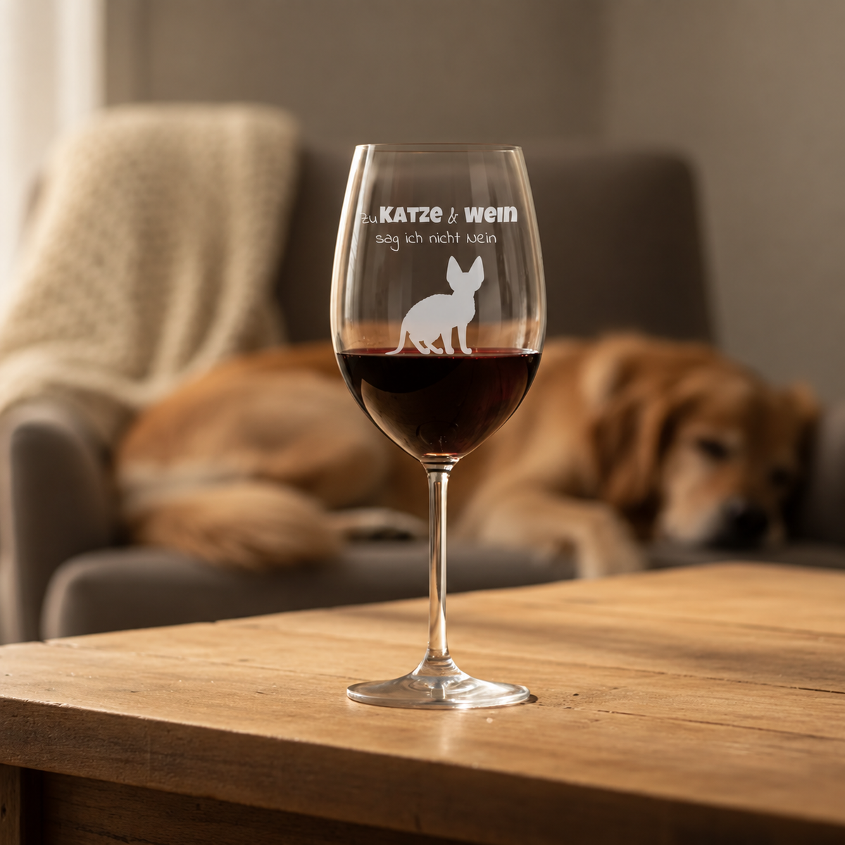 Gepersonaliseerd wijnglas met gegraveerde spreuk en kat, gevuld met rode wijn op een houten tafel.