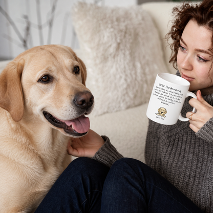 Personne avec un mug portant l'inscription "Liebe Hundemama" et un labrador retriever sur un canapé clair.