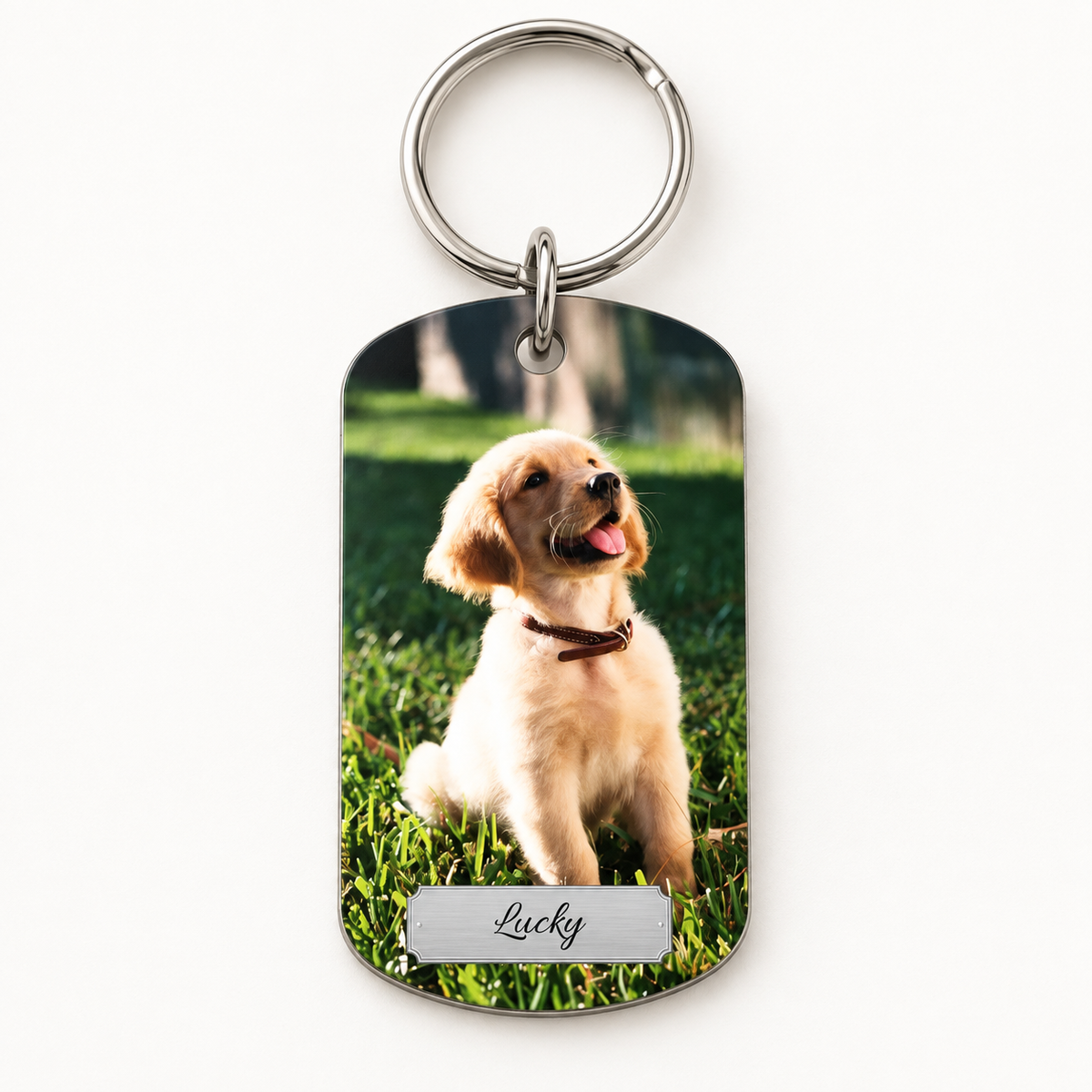 Gepersonaliseerde sleutelhanger met foto van een hond en gegraveerde naam op zilveren oppervlak.