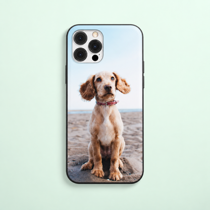 Coque de téléphone avec photo d'un chien assis sur la plage, bord noir.