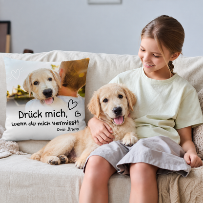 Gepersonaliseerd beige kussen met opdruk en hondenfoto, op een bank met een meisje en een hond.