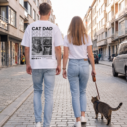 T-shirt blanc avec imprimé chat au dos, deux personnes et un chat se promenant dans une rue.