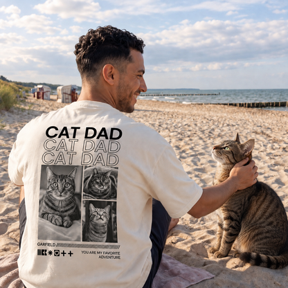 T-shirt beige avec l'inscription "Cat Dad" et motifs de chats au dos, porté par un homme sur la plage.