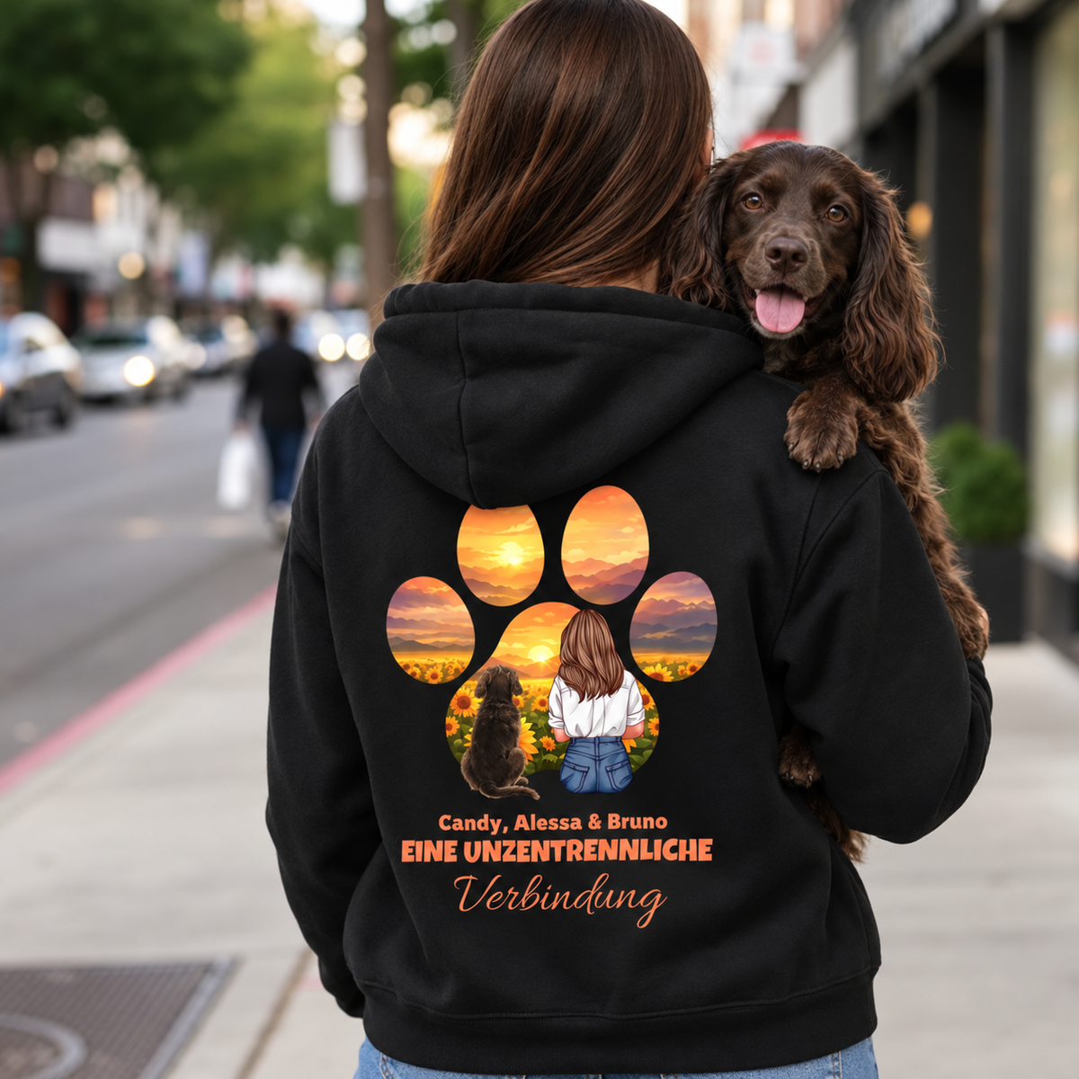 Zwarte hoodie met kleurrijk motief van persoon en hond en de tekst "Eine unzertrennliche Verbindung" op de rug.