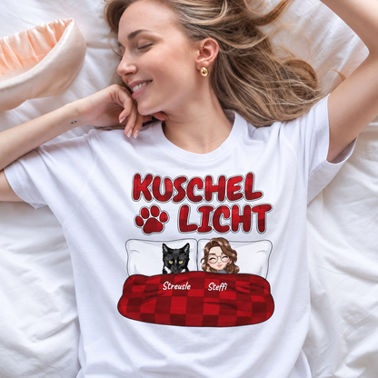 T-shirt blanc avec l'inscription "Kuschel Licht" et un dessin d'une femme et d'un chat au lit.