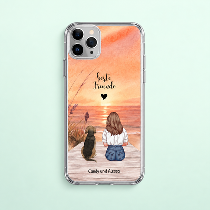 Gepersonaliseerd transparant telefoonhoesje met illustratie van een meisje en hond op het strand bij zonsondergang.