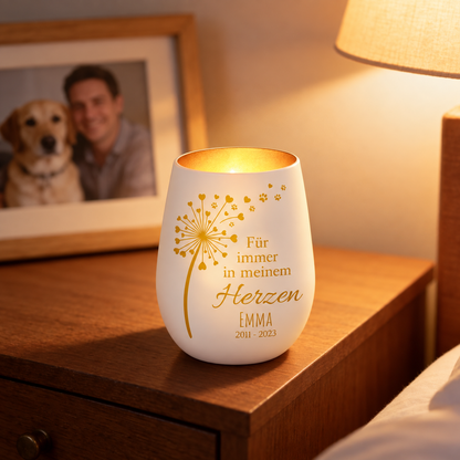 Gepersonaliseerd wit keramisch herdenkingslicht met gouden letters en bladontwerp, op een nachtkastje.