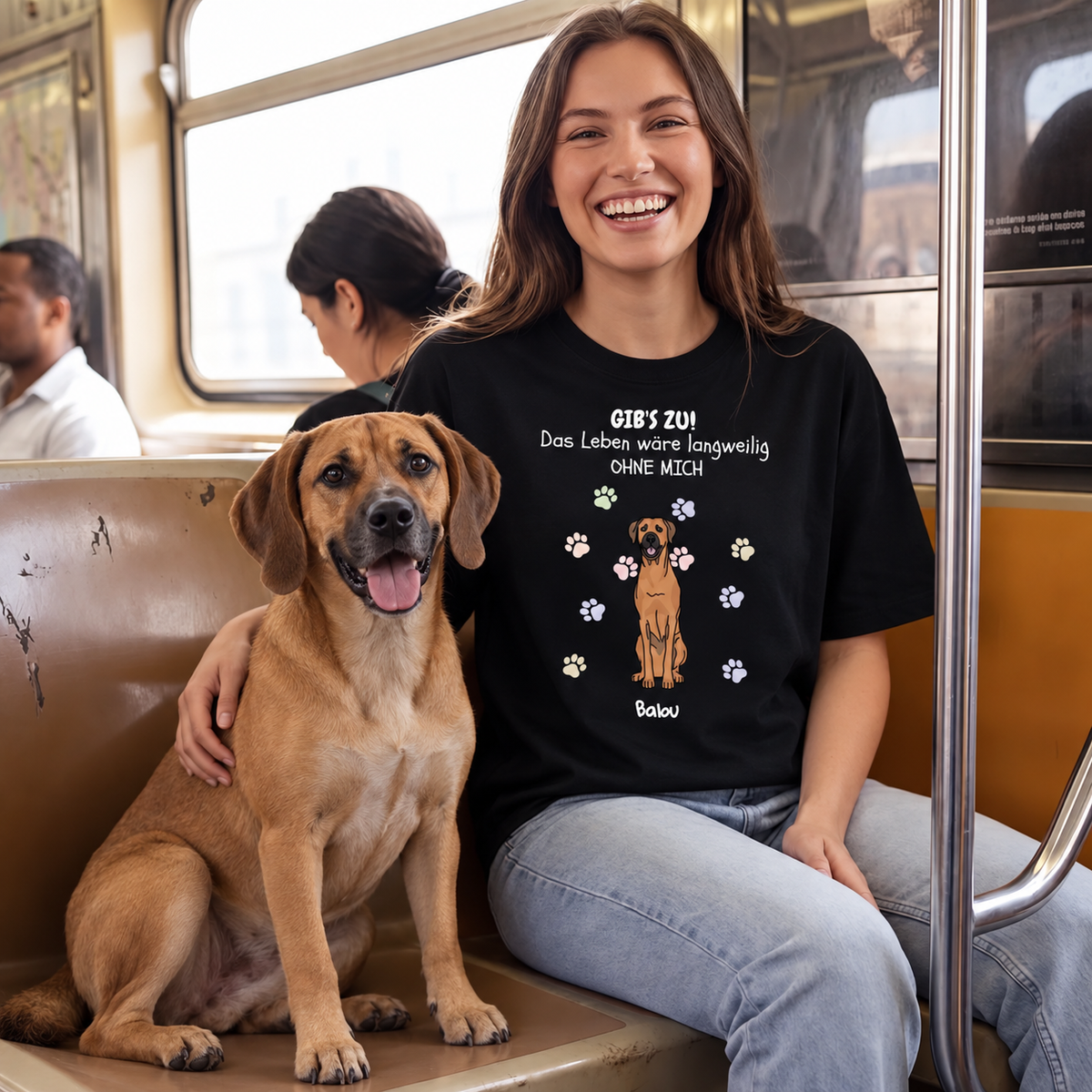 T-shirt noir avec impression, texte et photo de chien, porté par une femme souriante dans un train. Chien assis à côté.