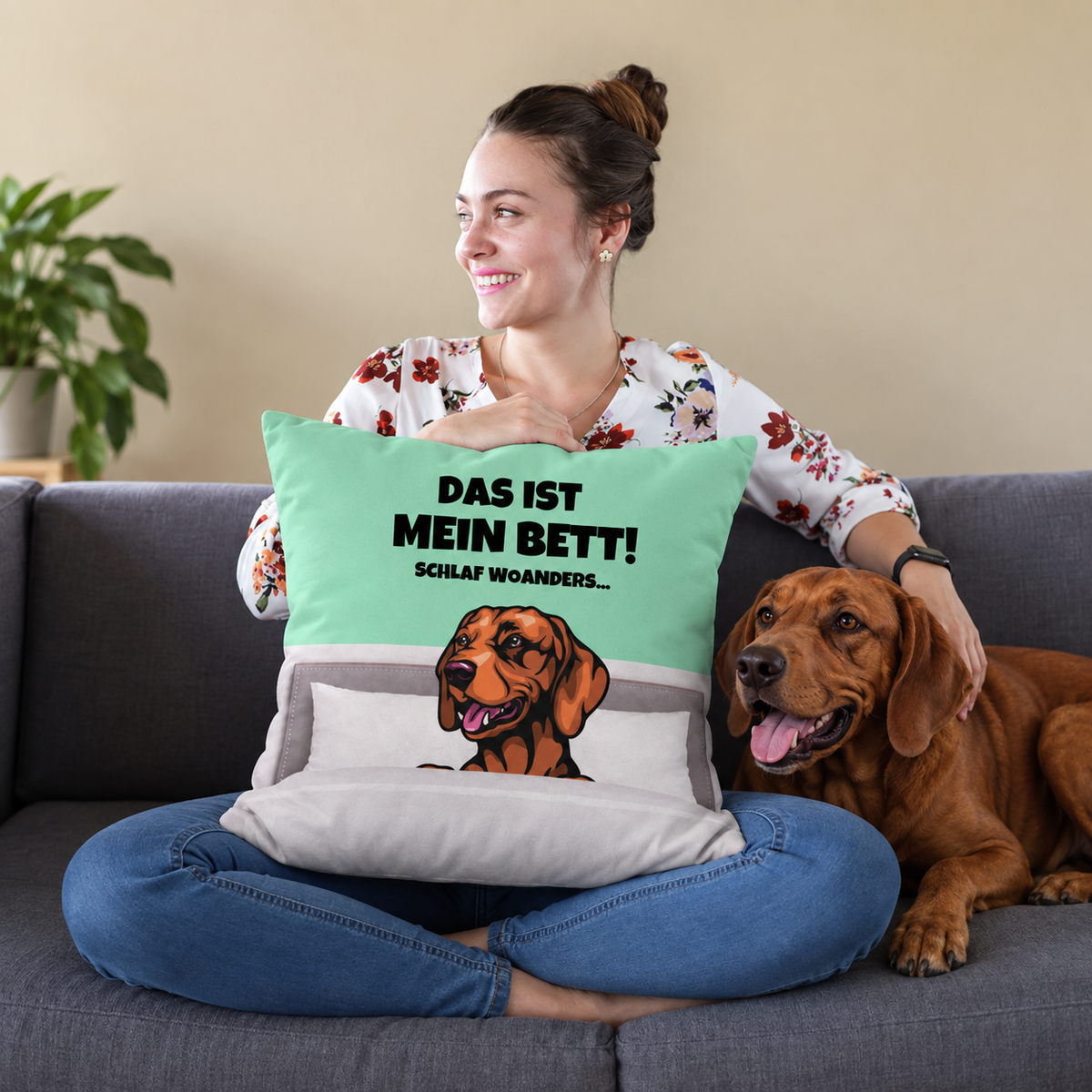 Gepersonaliseerd kussen met hondenmotief en tekst in mintgroen en grijs, op een bank met een vrouw en een hond.