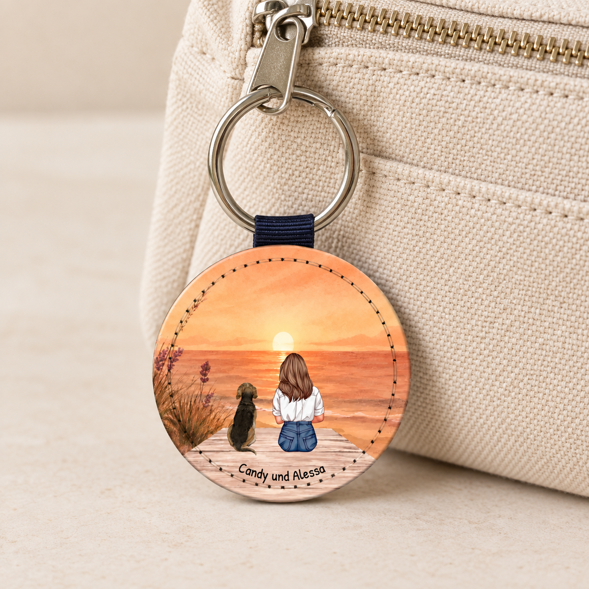 Gepersonaliseerde sleutelhanger met illustratie van een vrouw en een hond voor een zonsondergang.