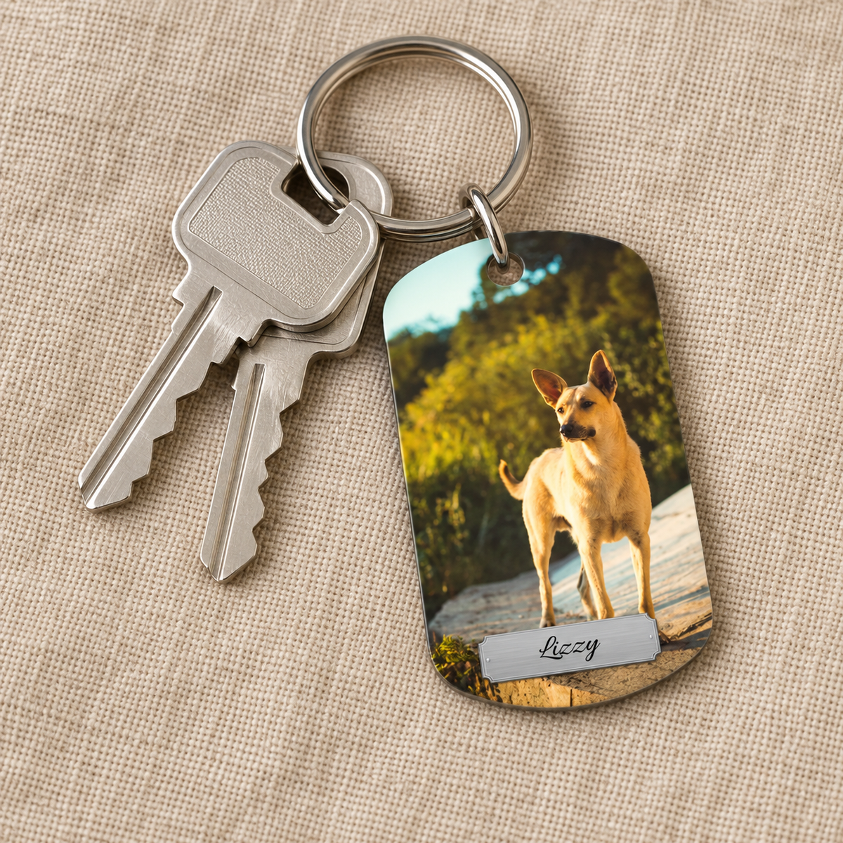 Gepersonaliseerde sleutelhanger met foto van een hond en gegraveerde naam, met twee sleutels.