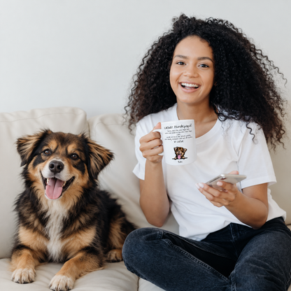Vrouw met gepersonaliseerde mok "Lieber Hundepapa" zit naast een hond op een bank. Mok toont hondenfoto en tekst.