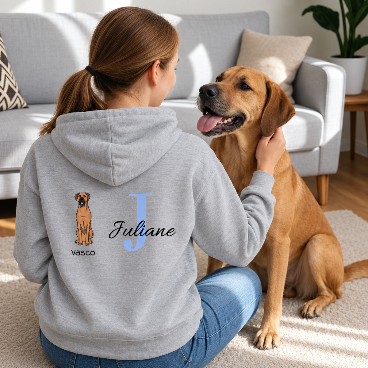 Grijze hoodie met gepersonaliseerde rug: hond en de naam "Juliane" in blauwe letters.