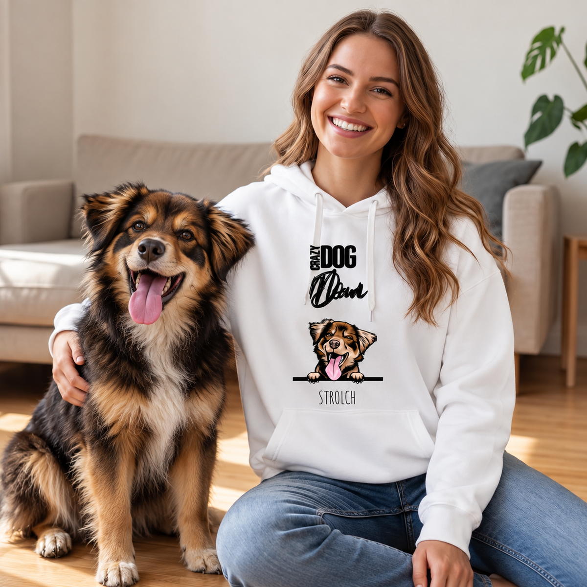 Lachende persoon in witte hoodie met hond op een houten vloer in een huiselijke sfeer. Hoodie toont hondenafbeelding.