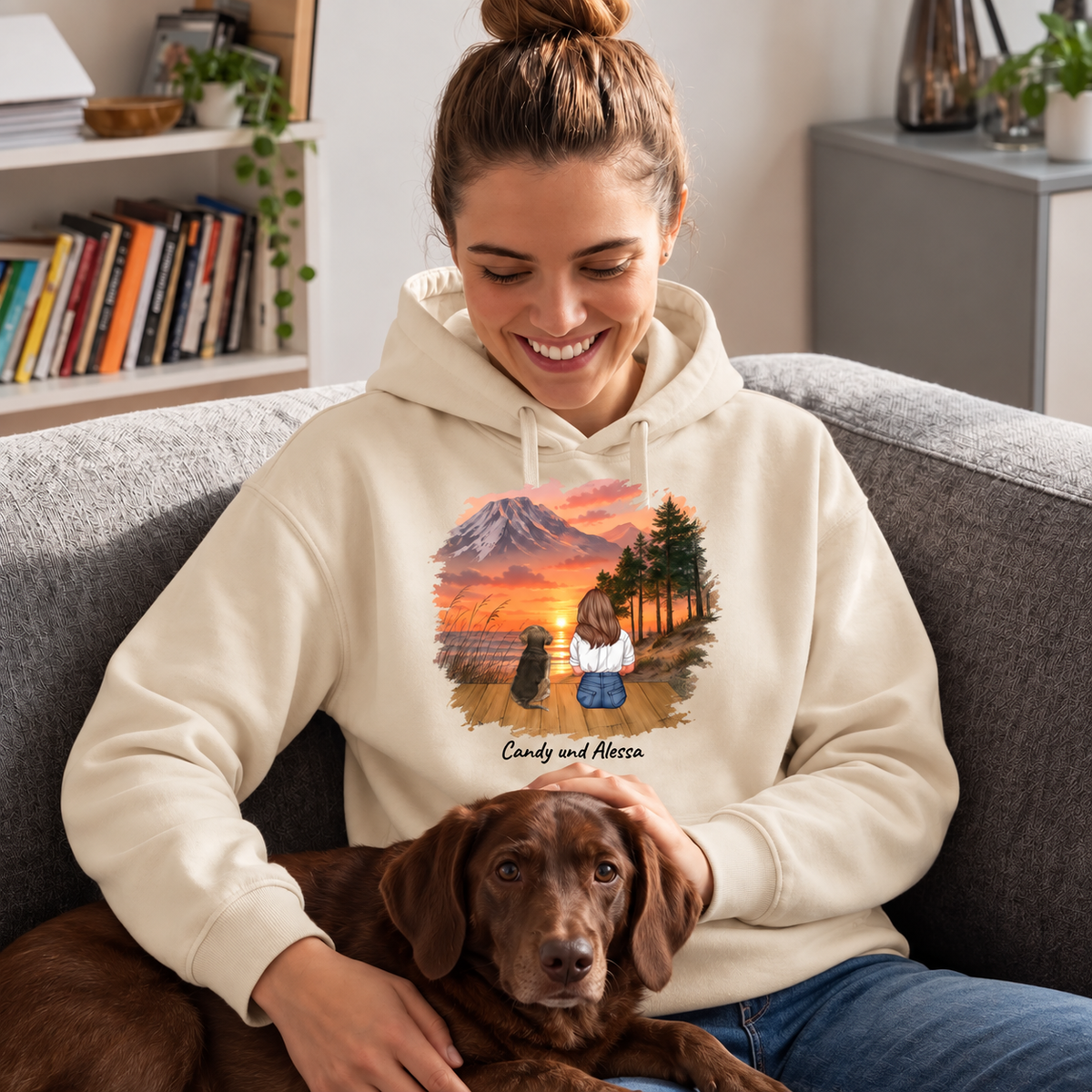 Sweat à capuche beige avec impression personnalisée d'une femme et d'un chien au coucher du soleil, assise sur un canapé avec un chien.