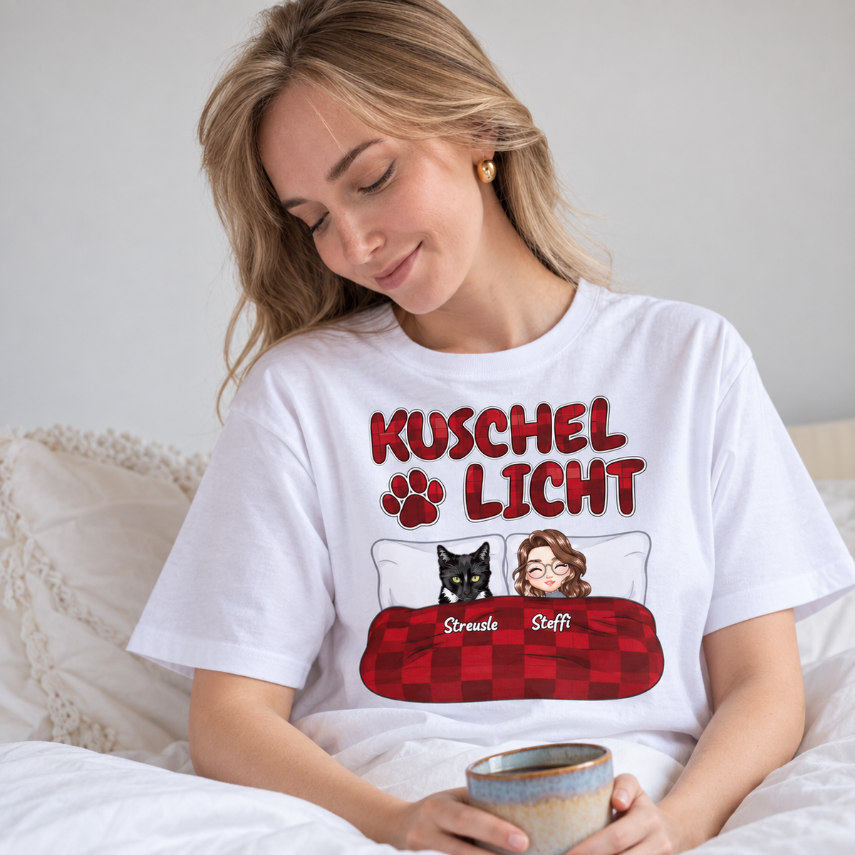 T-shirt blanc avec l'inscription "Kuschel Licht" et illustrations d'une femme et d'un chat au lit.