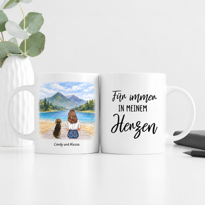 Gepersonaliseerde witte mok met illustratie van een vrouw en een hond bij een meer en de tekst "Für immer in meinem Herzen".