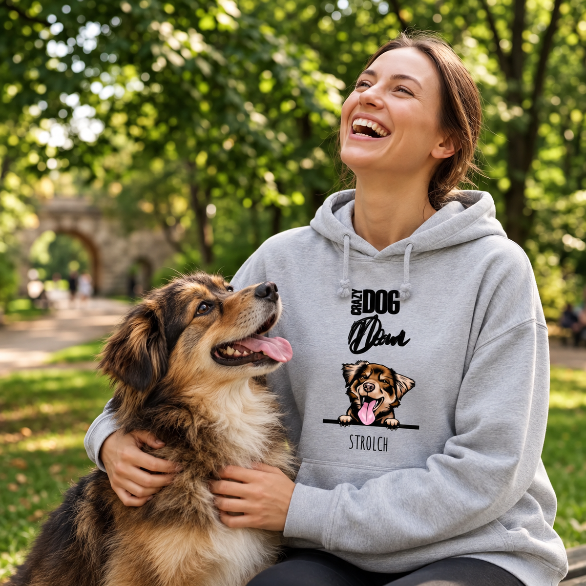 Grijze hoodie met hondenmotief, gedragen door een lachende vrouw die met haar hond speelt in het park.