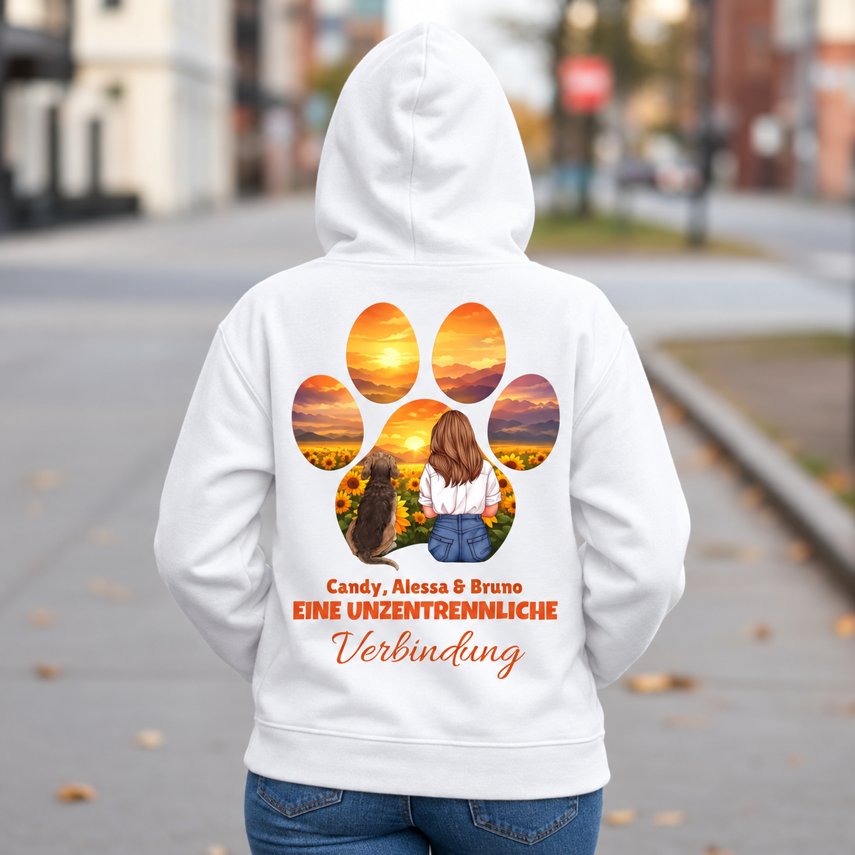 Witte hoodie met opdruk van een persoon en hond bij zonsondergang, tekst: "Eine unzertrennliche Verbindung".