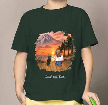 Donkergroen kindershirt met kleurrijke print van een meisje en een hond bij zonsondergang.