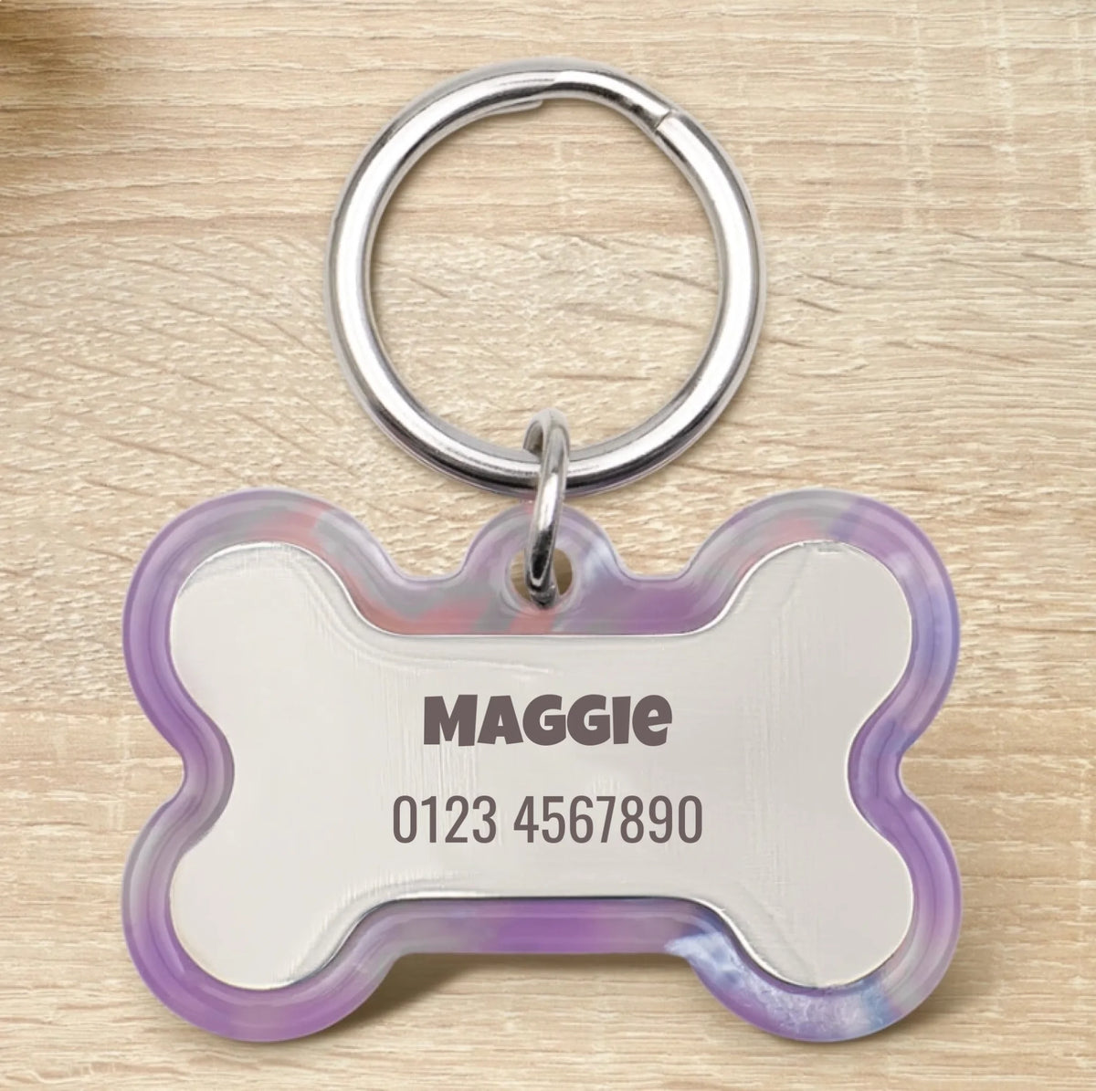 Médaille pour chien personnalisée en résine époxy en forme d'os avec anneau argenté et bord violet transparent.
