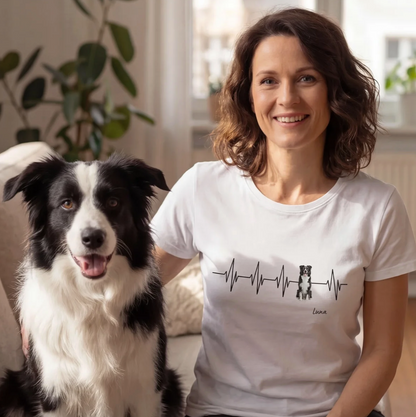 Wit T-shirt met hartslagontwerp en hondenmotief, personalisatie mogelijk. Vrouw zit met hond op een bank.