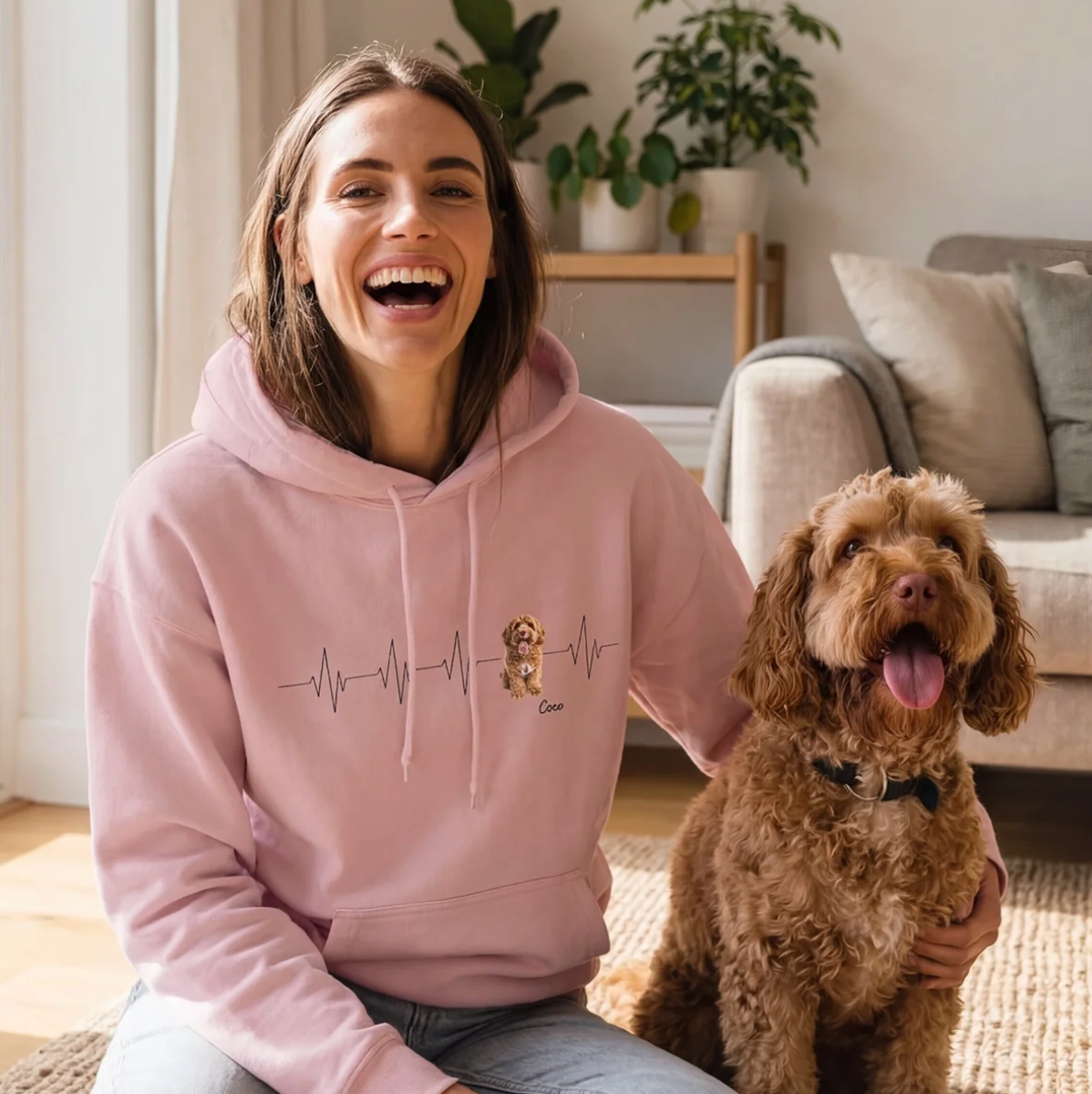 Personne en sweat à capuche rose avec motif battement de cœur, assise sur un tapis à côté d'un chien.
