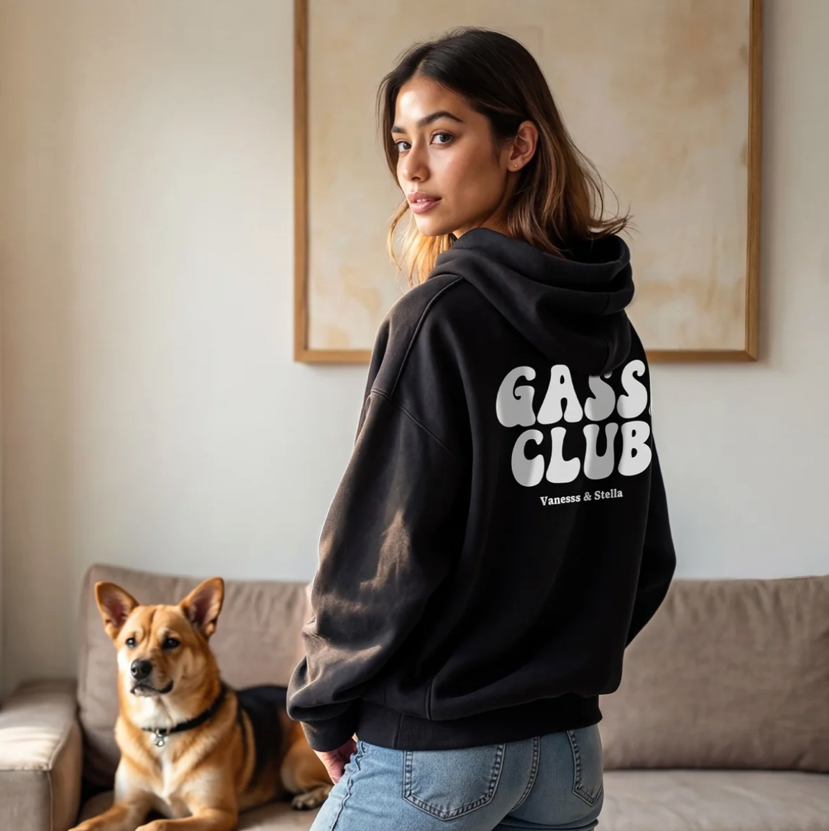 Zwarte hoodie met opdruk "GASS CLUB" op de rug, persoon staat met een hond in een moderne woonkamer.