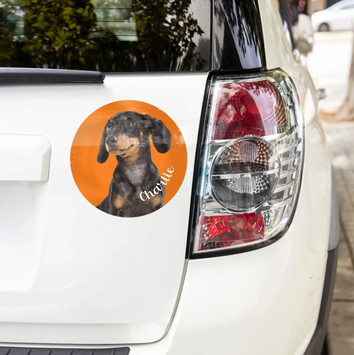 Gepersonaliseerde autosticker met afbeelding van een teckel op oranje achtergrond, op een witte auto.