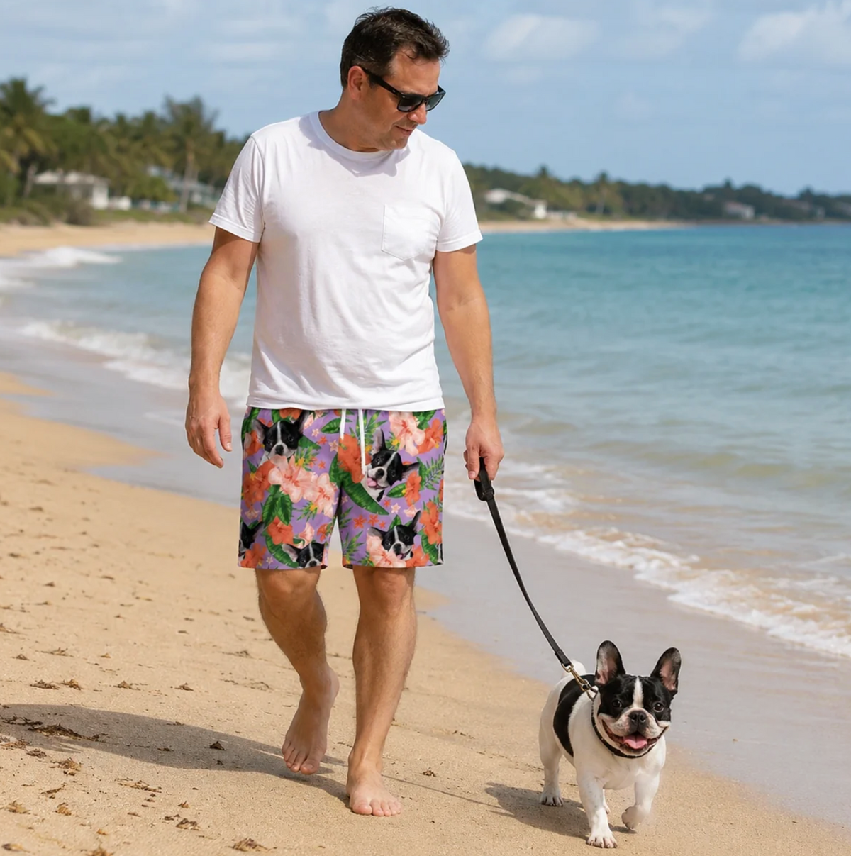 Man in gepersonaliseerde zwembroek met kleurrijk bloemen- en dierenpatroon, loopt blootsvoets over het strand.