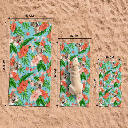 Drie gepersonaliseerde strandhanddoeken met hondenmotief en kleurrijke bloemen op het zand.