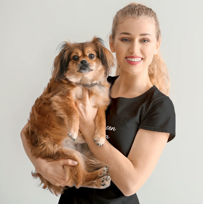 Vrouw houdt een kleine hond in haar armen, draagt een gepersonaliseerd zwart T-shirt.