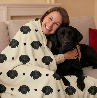 Gepersonaliseerde deken met zwarte hondenkopjes op beige achtergrond, om een lachende vrouw gewikkeld.