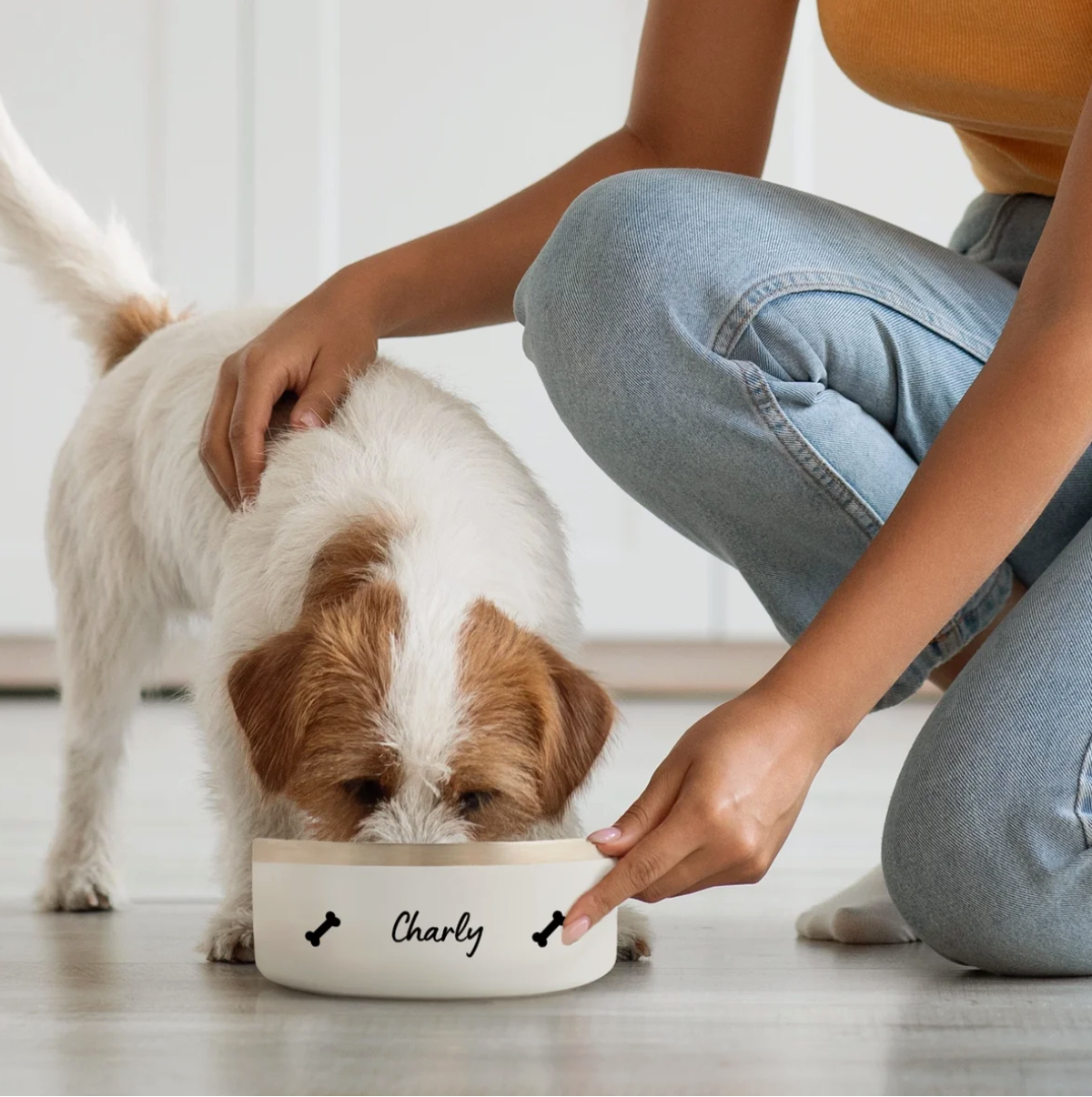Chien mangeant dans une gamelle blanche personnalisée avec le nom "Charly" et des motifs d'os.