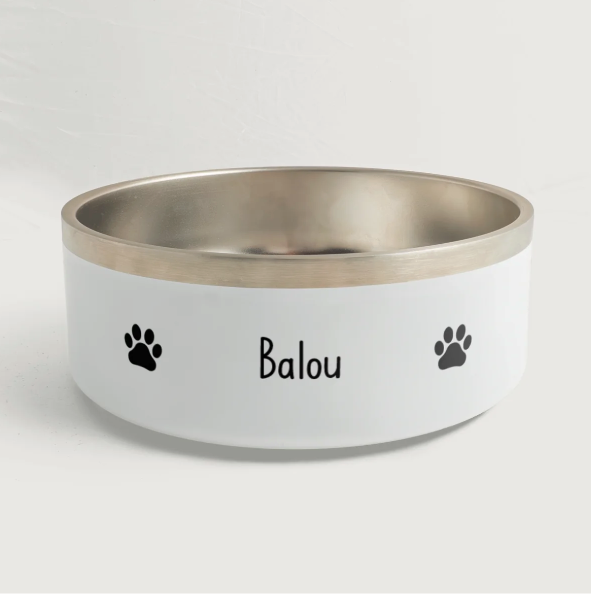 Gamelle personnalisée avec bord argenté, le prénom "Balou" et des empreintes de pattes noires.