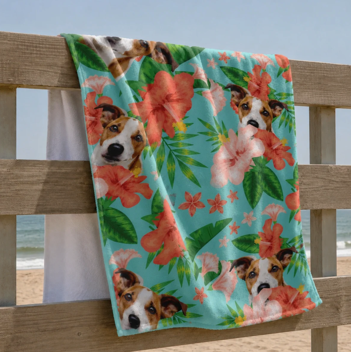 Gepersonaliseerde strandhanddoek met hondenmotief en kleurrijke bloemen op lichtblauwe achtergrond.