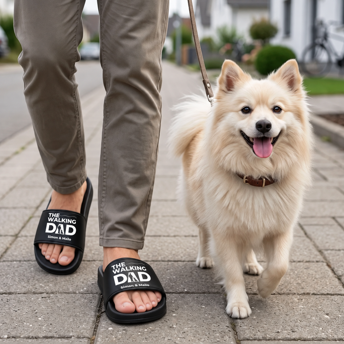 Persoon draagt gepersonaliseerde zwarte badslippers met opdruk "THE WALKING DAD" en loopt met een hond.