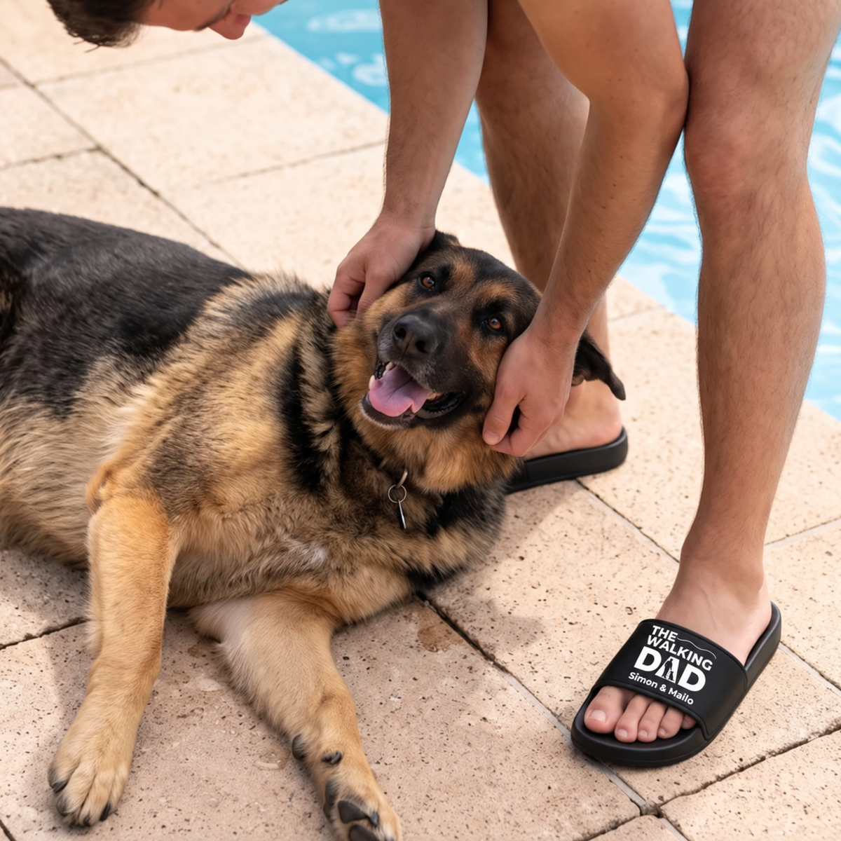 Persoon draagt zwarte badslippers met opdruk "THE WALKING DAD" en zit naast een hond bij het zwembad.